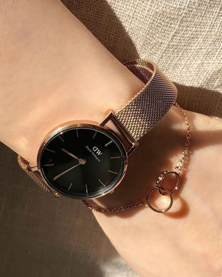 Cận cảnh đồng hồ DW Petite vàng mặt đen với dây thép lưới vàng hồng tinh tế