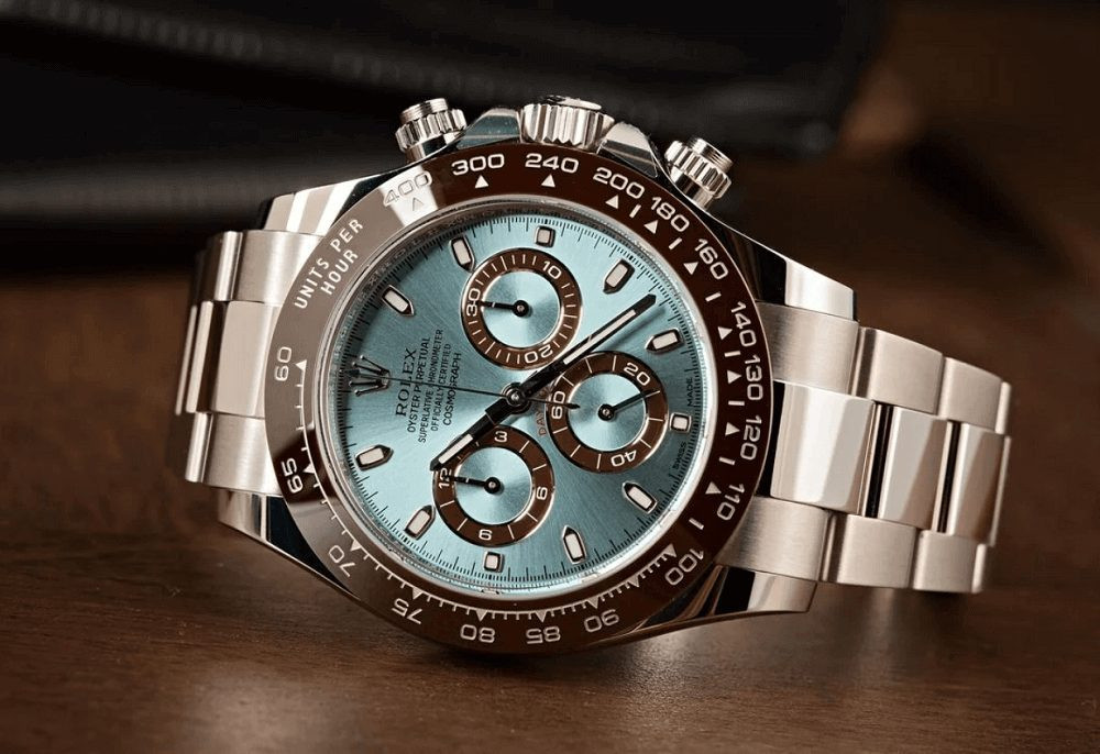 Chiếc đồng hồ Rolex Daytona 116506 bạch kim với mặt số xanh lam và viền ceramic nâu nhạt, thể hiện vẻ đẹp sang trọng và đắt giá.