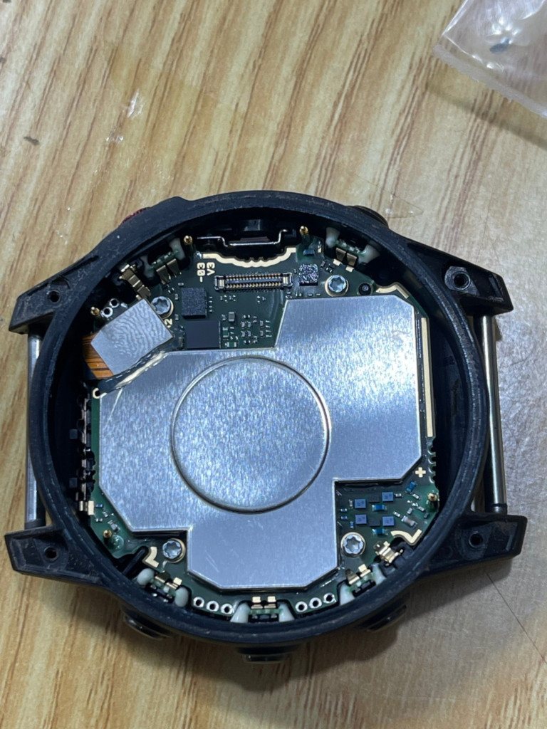Bo mạch và ốc vít đồng hồ Garmin Epix Gen 2 bị cong vênh do áp lực từ máy giặt, minh họa sự cố cần sửa đồng hồ Garmin