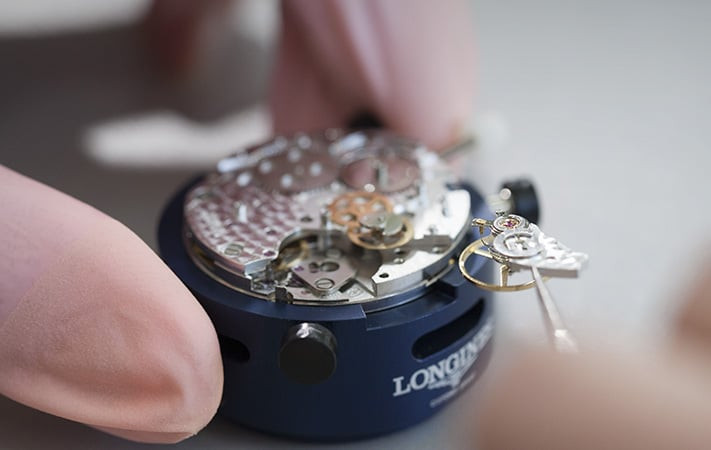 Kỹ thuật viên đang kiểm tra bộ máy đồng hồ cơ Longines, cần thiết khi tìm hiểu tại sao đồng hồ cơ hay bị chết