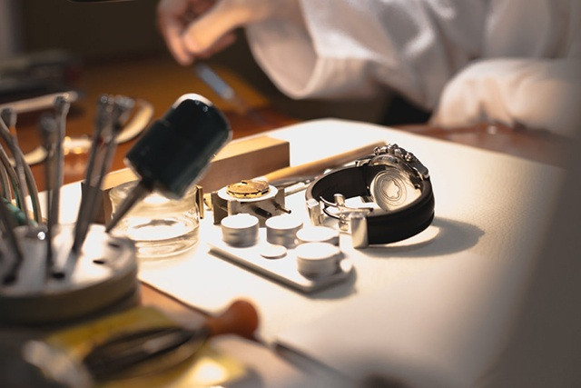 Kỹ thuật viên đang kiểm tra mặt kính đồng hồ Rolex bị hư hỏng trước khi tiến hành thay thế